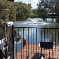 sun shining on a lovely deck overlooking a dam with a fountain.