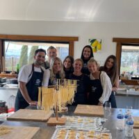 A cooking class group with fresh pasta drying on racks