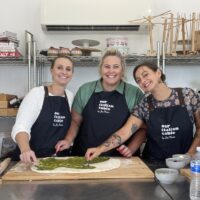 Three guests making pasta at the kitchen bench