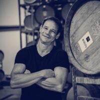 Winemaker Adam Kossak beside the barrels